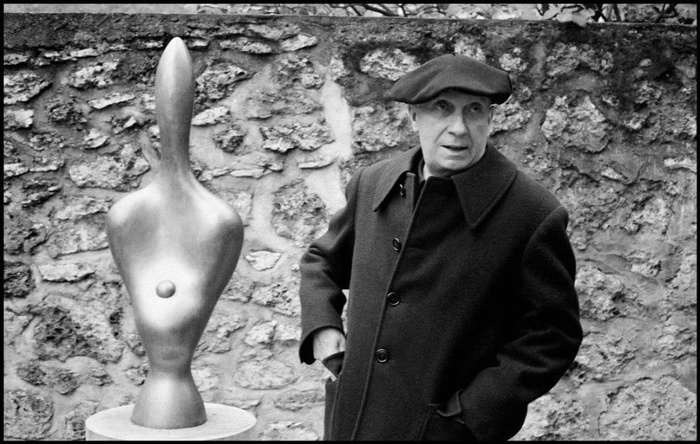 Artwork Title: Artist Jean Arp with one of his sculptures behind him, Paris, France